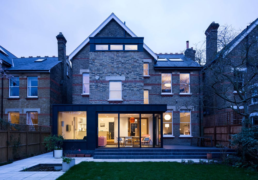 Contemporary brick home featuring extensive aluminium sliding doors and windows flooding the open-plan living space with natural light.