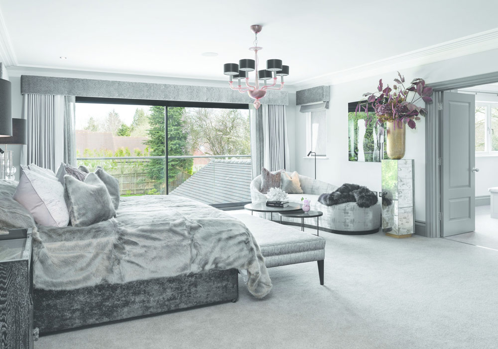 Luxurious bedroom with aluminium sliding doors opening onto a wooden deck, maximising natural light and garden views.