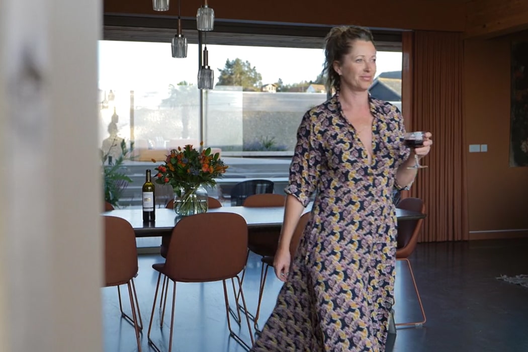 Woman holding wine glass in modern open-plan kitchen with theEDGE2 slimline glass sliding doors opening onto countryside views