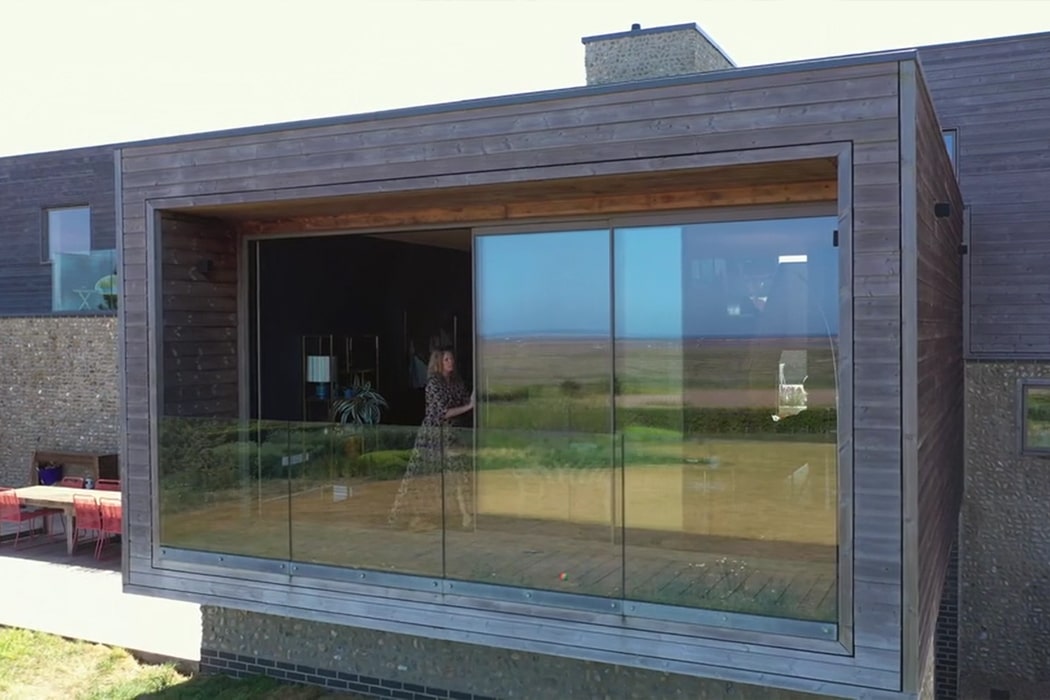 theEDGE2.0 ultra-slimline glass sliding door opening onto a countryside view, showcasing minimal framing and seamless indoor-outdoor connection.
