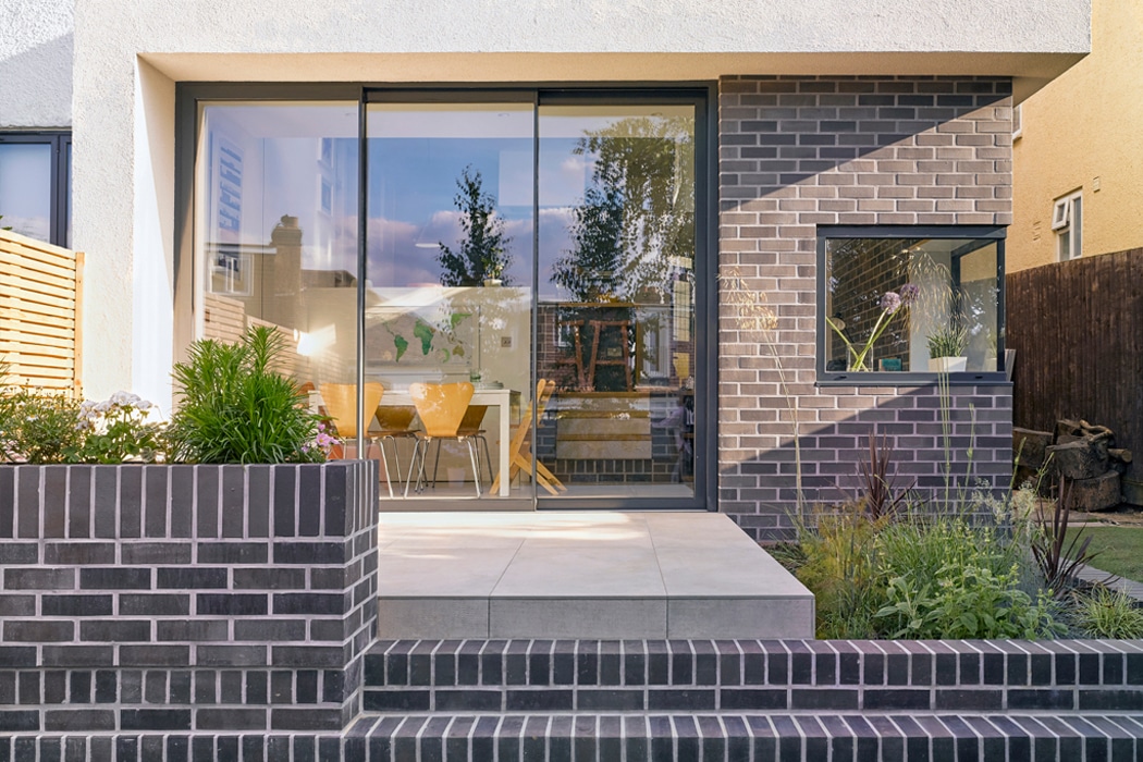 theEDGE2.0 ultra-slimline glass sliding door opens onto a contemporary patio, maximising light and garden views with its narrow aluminium frame.