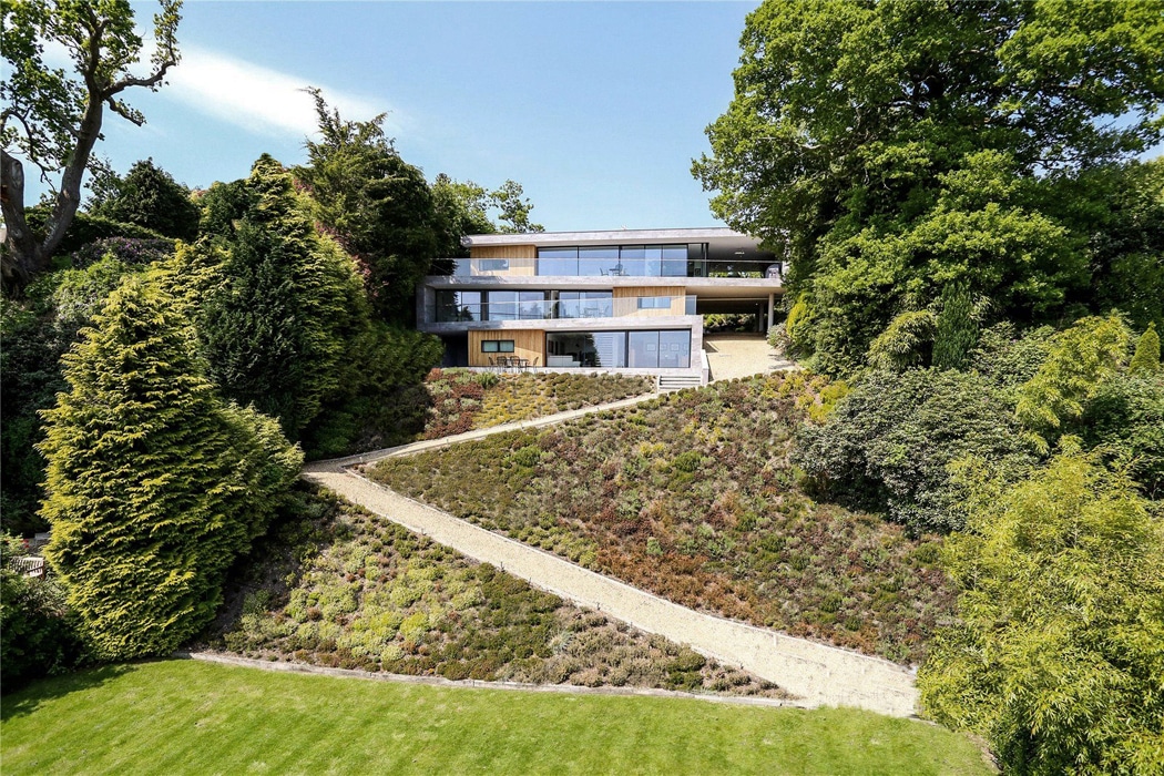 Modern three-storey house with theEDGE2.0 slimline glass sliding doors opening onto landscaped gardens with green hedging and sedum planting.