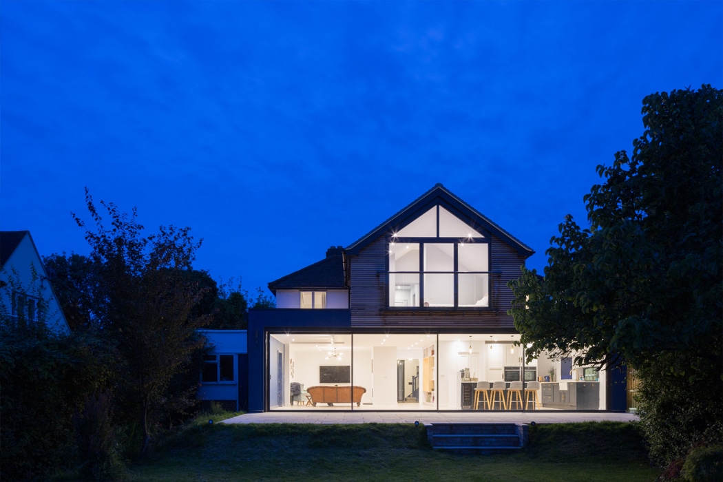 Modern house extension at dusk featuring theEDGE2.0 ultra-slimline glass sliding doors, flooding the interior with light and revealing open-plan living spaces within.