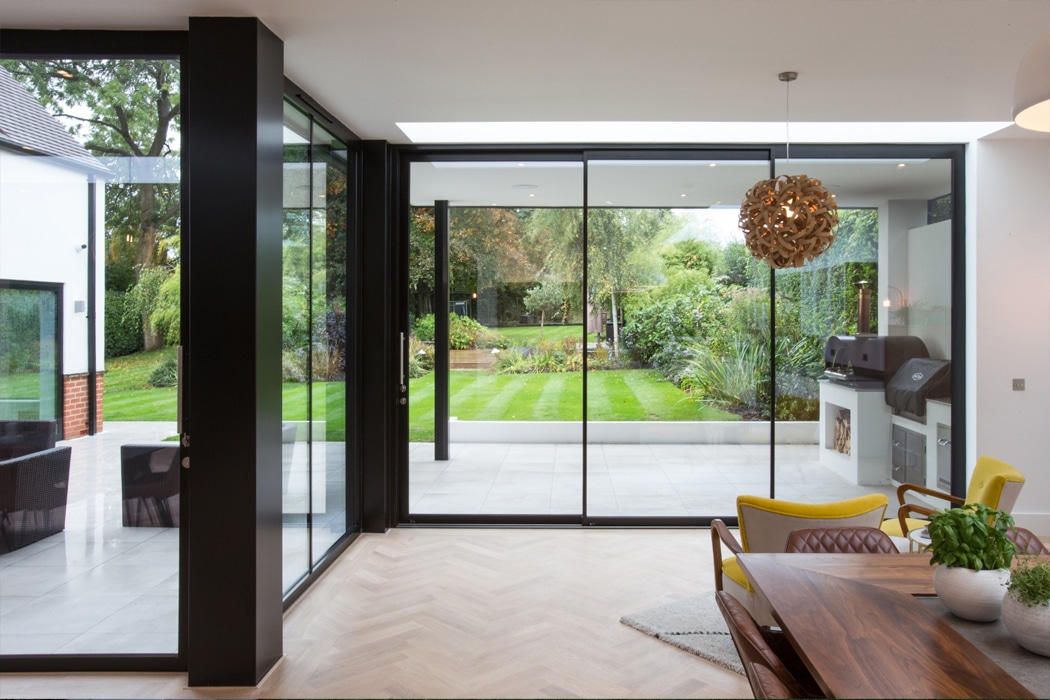 Modern home extension featuring EDGE2.0 sliding doors opening onto manicured garden, showcasing standard UK bifold and sliding door sizing for residential spaces.