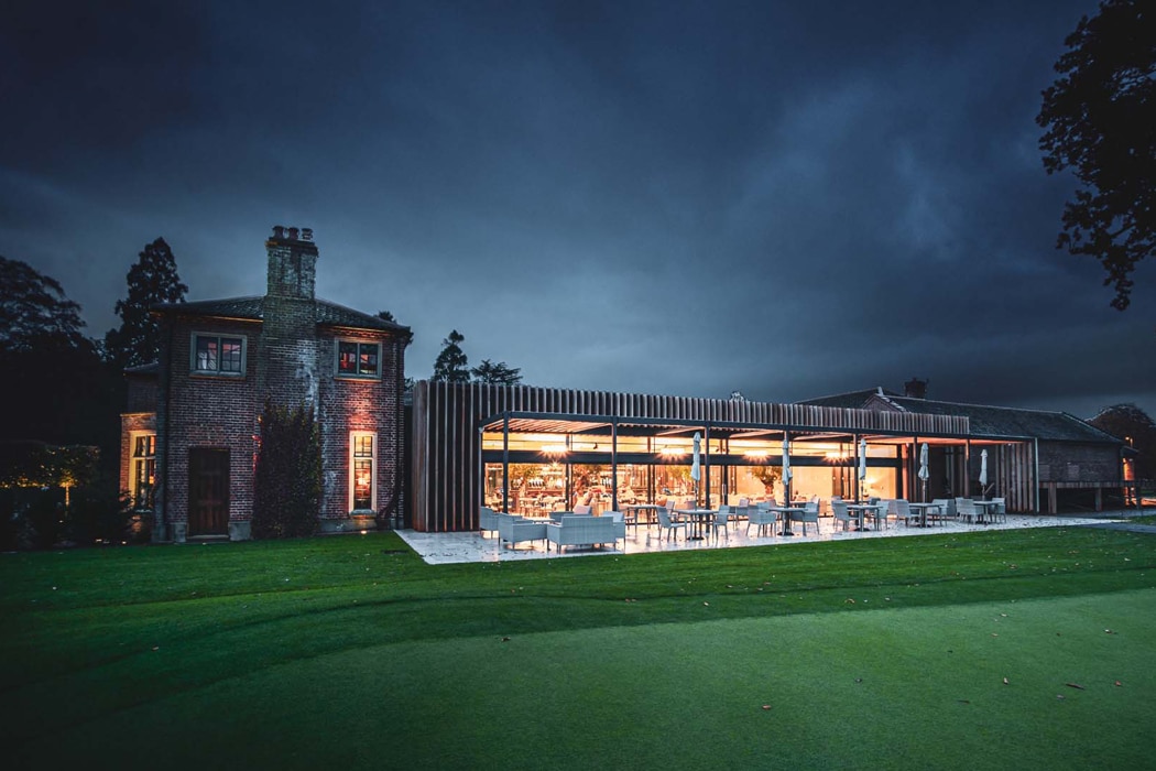 theEDGE2 ultra-slimline glass sliding doors illuminating a modern brick extension at dusk, seamlessly connecting interior spaces to manicured gardens.