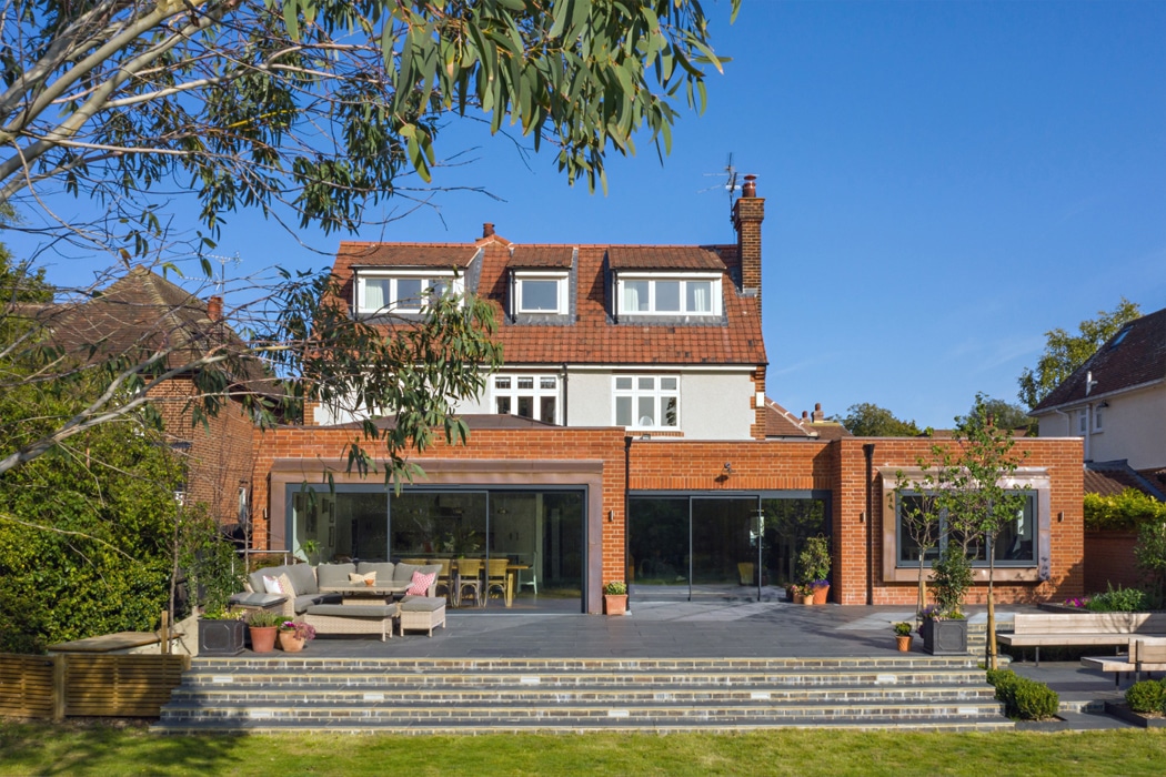 Modern brick extension with theEDGE2.0 ultra-slimline glass sliding doors opening onto a paved terrace and garden area.