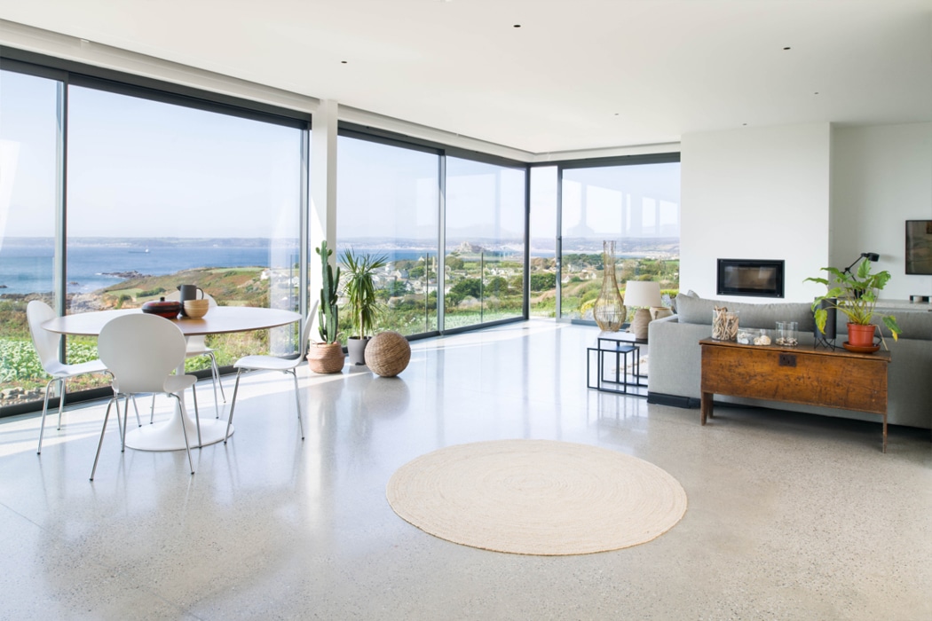 Modern open-plan living space with theEDGE2.0 glass sliding doors offering panoramic coastal and countryside views through ultra-slim frames.
