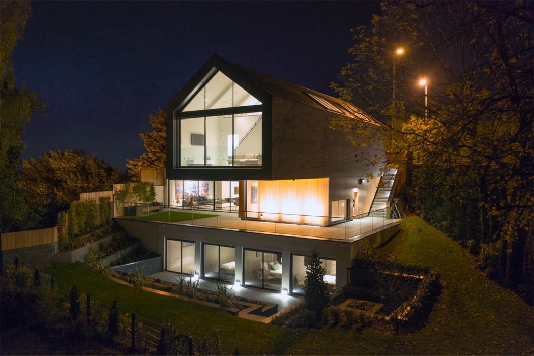 Modern house at night featuring theEDGE2.0 ultra-slimline glass sliding doors opening onto an illuminated terrace, maximising light and views.