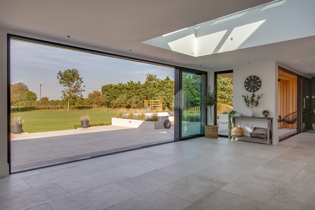 theEDGE2.0 ultra-slimline glass sliding door opening onto a modern terrace and manicured garden, maximising natural light and outdoor views.